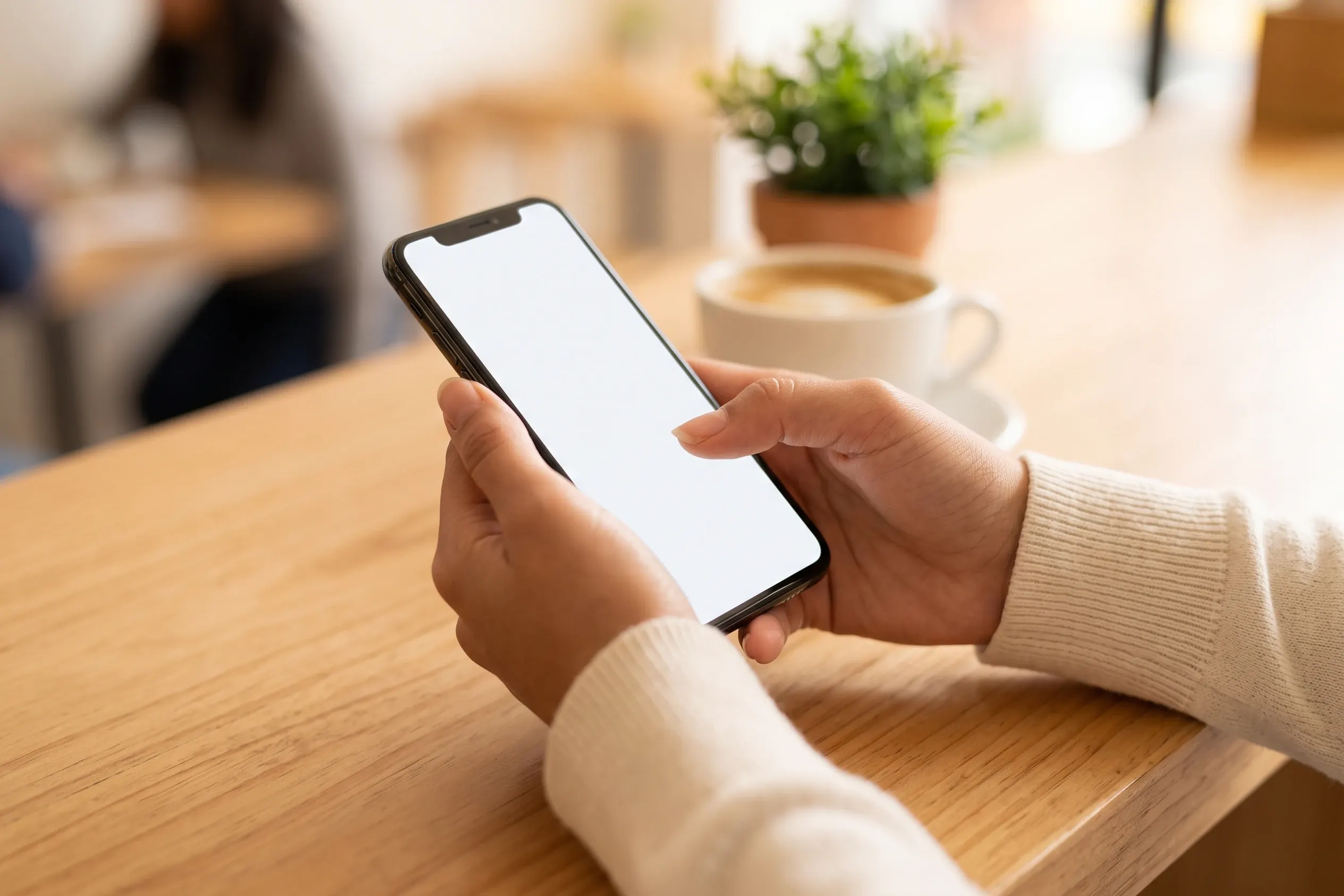 Manos con un celular sobre la barra de madera de un café